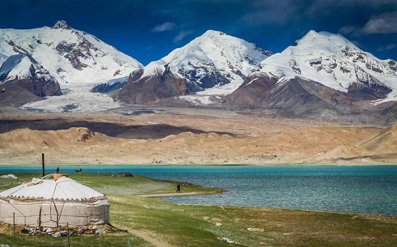 A yurt by the Karakul Lake with a backdrop of snow-covered peaks